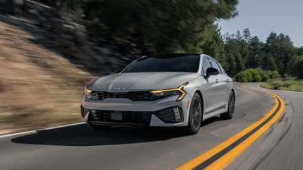 2025 Kia K5 GT frente 3/4 tiro de ação dirigindo na estrada.