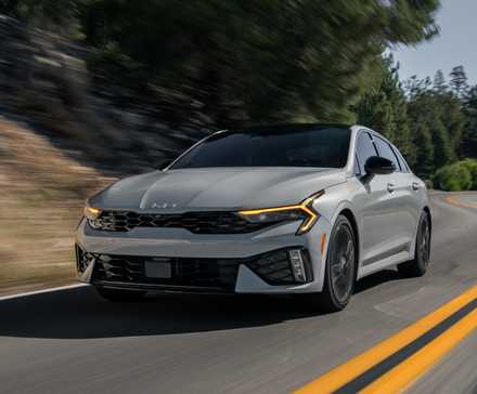2025 Kia K5 GT front 3/4 action shot driving on the road.