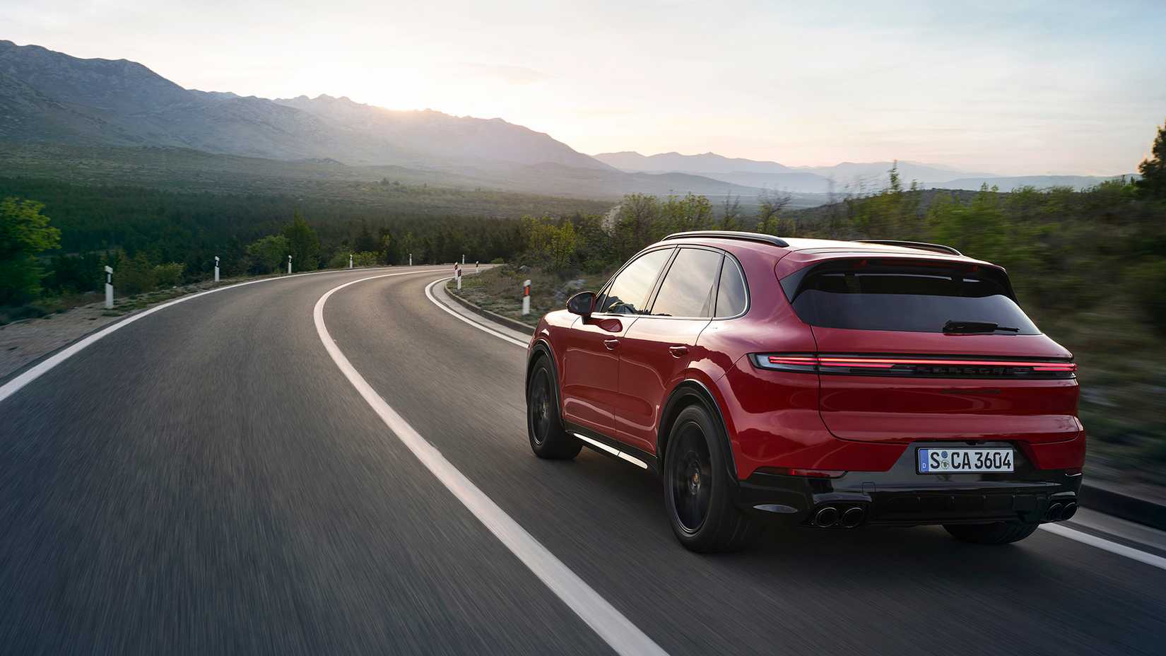Rear 3/4 action shot of the 2025 Porsche Cayenne GTS driving on the road
