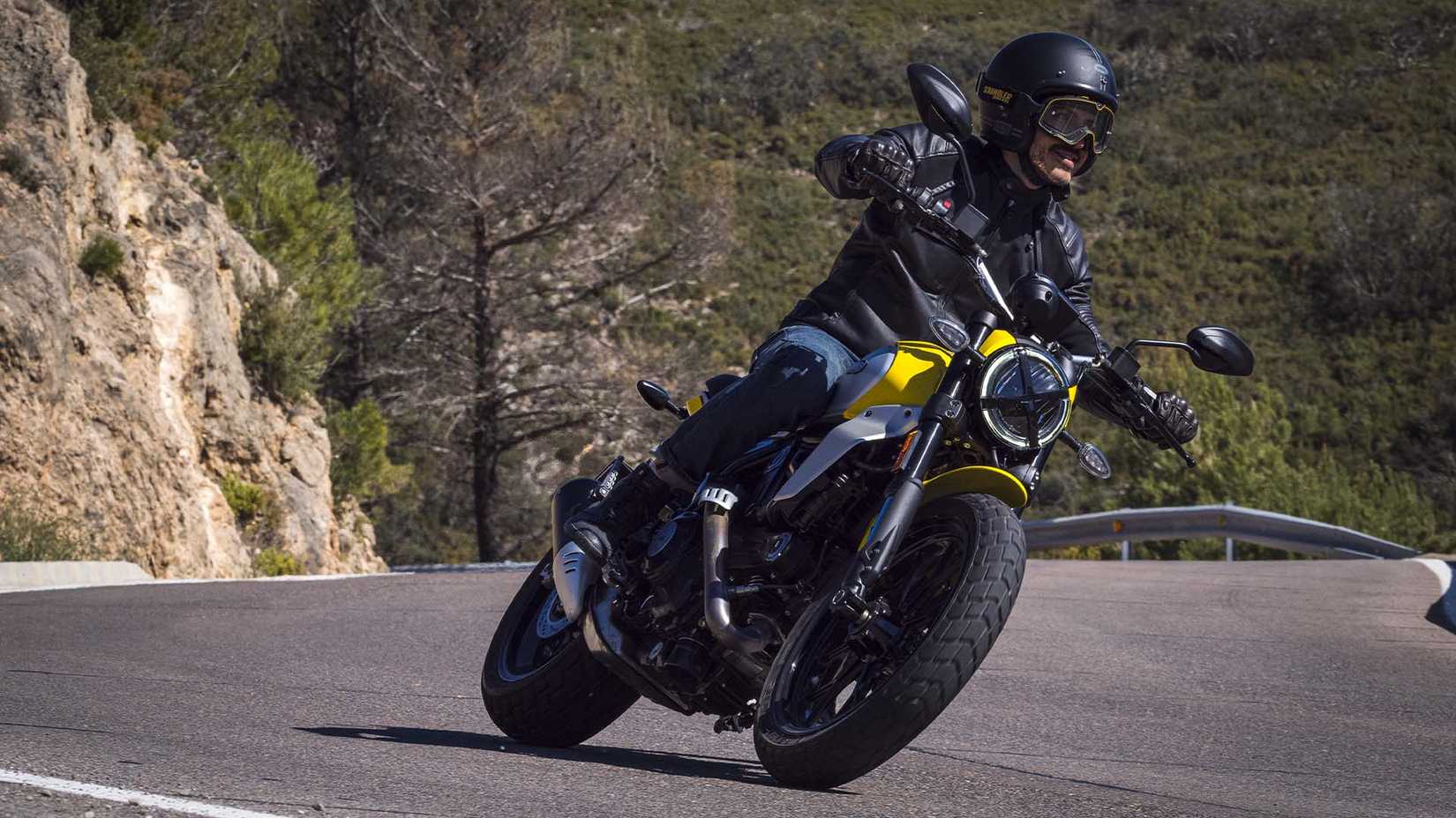 Yellow Ducati Scrambler icon taking a turn in the valleys