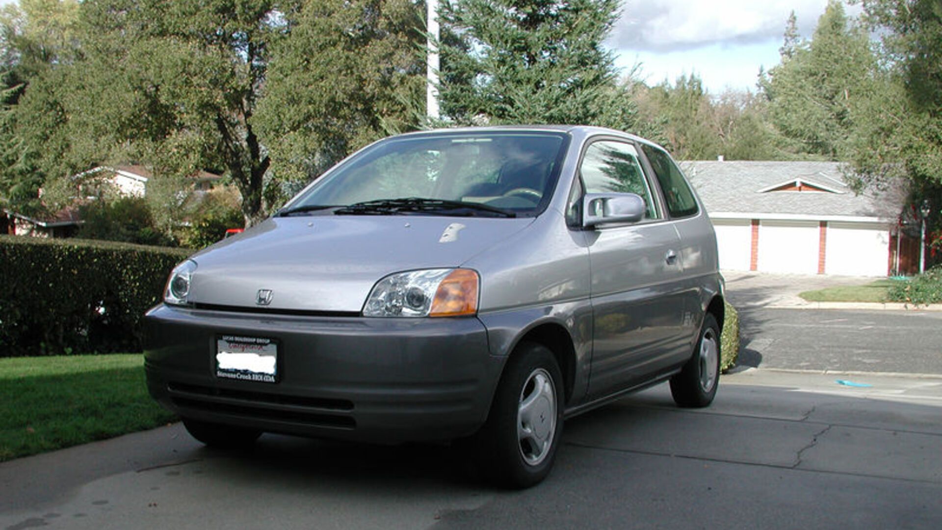 Front three-quarters shot of a Honda EV Plus parked in a driveway