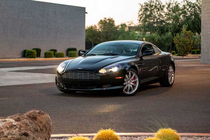 Black 2005 Aston Martin DB9 Coupe Parked With Lights On Front 3/4 View