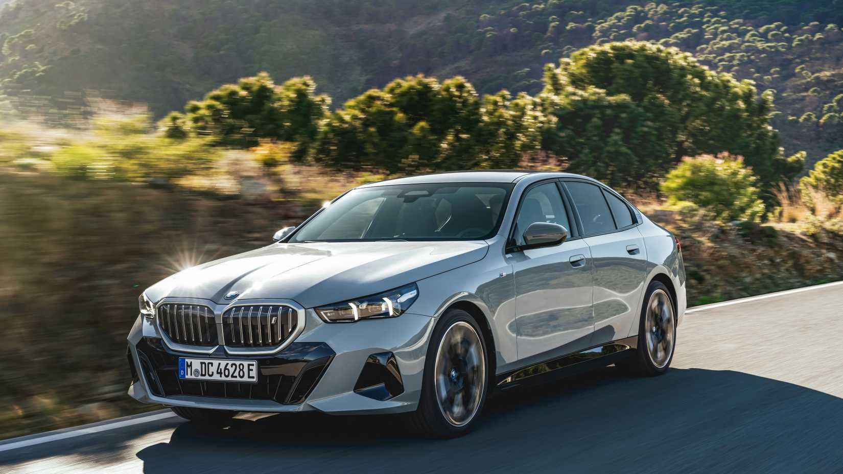 Silver 2024 BMW 5 Series Driving in the Sun