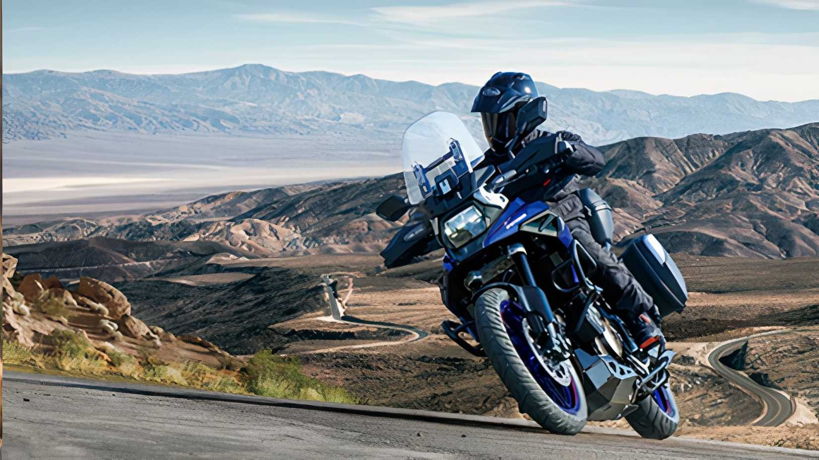 Uma Suzuki V-Strom 1050 XT cinza em uma estrada sinuosa de montanha
