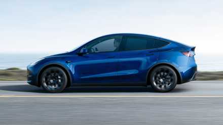 Uma foto de ação do perfil lateral de um Tesla Model Y azul