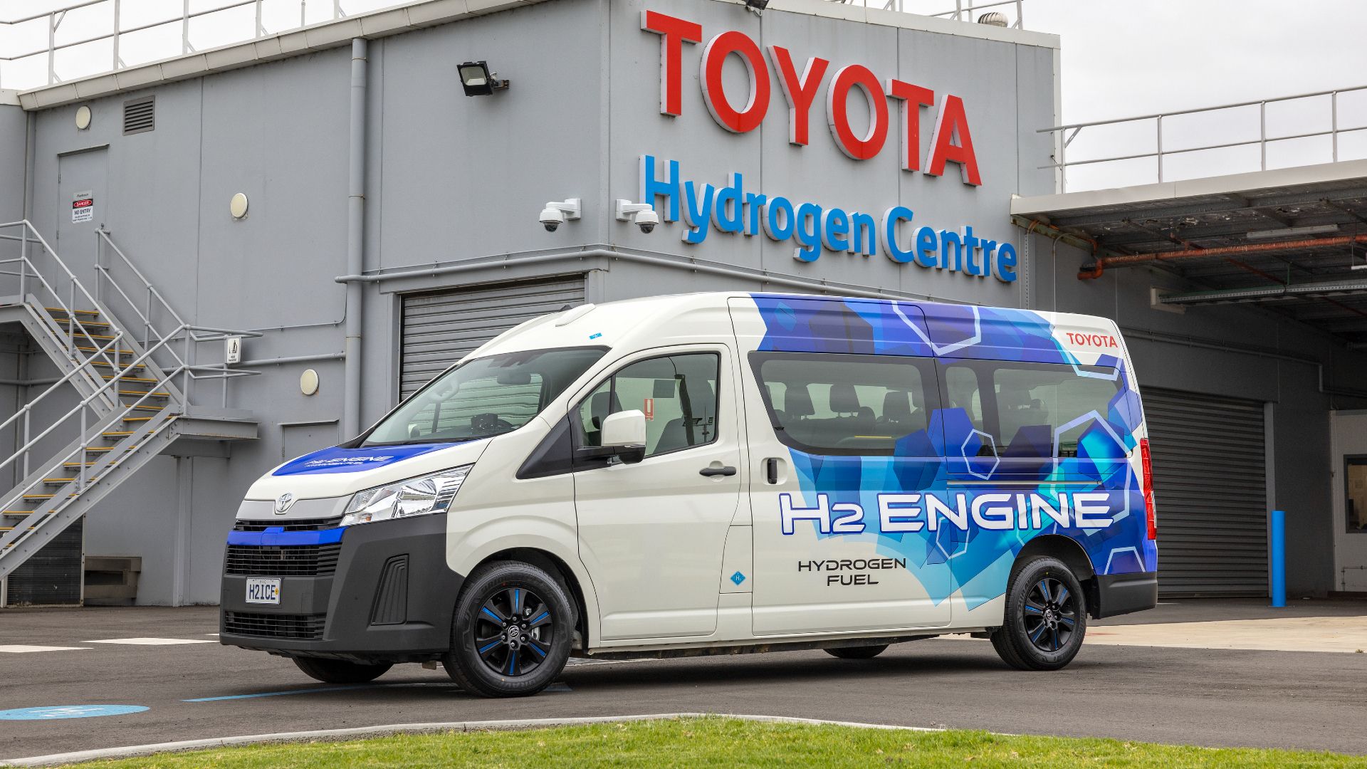 Foto frontal de um protótipo Toyota HiAce Hydrogen estacionado em frente a uma instalação da Toyota na Austrália 