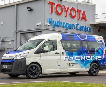 Foto frontal de um protótipo Toyota HiAce Hydrogen estacionado em frente a uma instalação da Toyota na Austrália