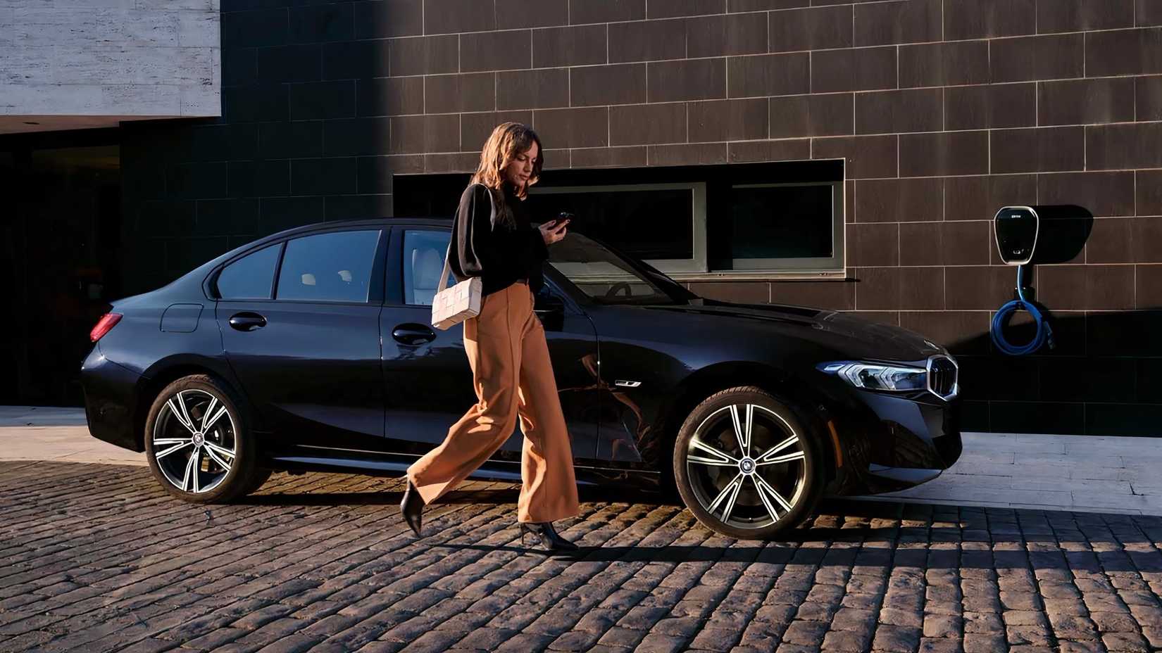 A woman walking beside a 2024 BMW 330e