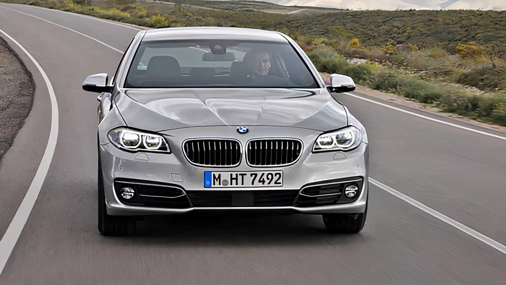 Front shot of a silver 2016 BMW 5-Series driving down the road