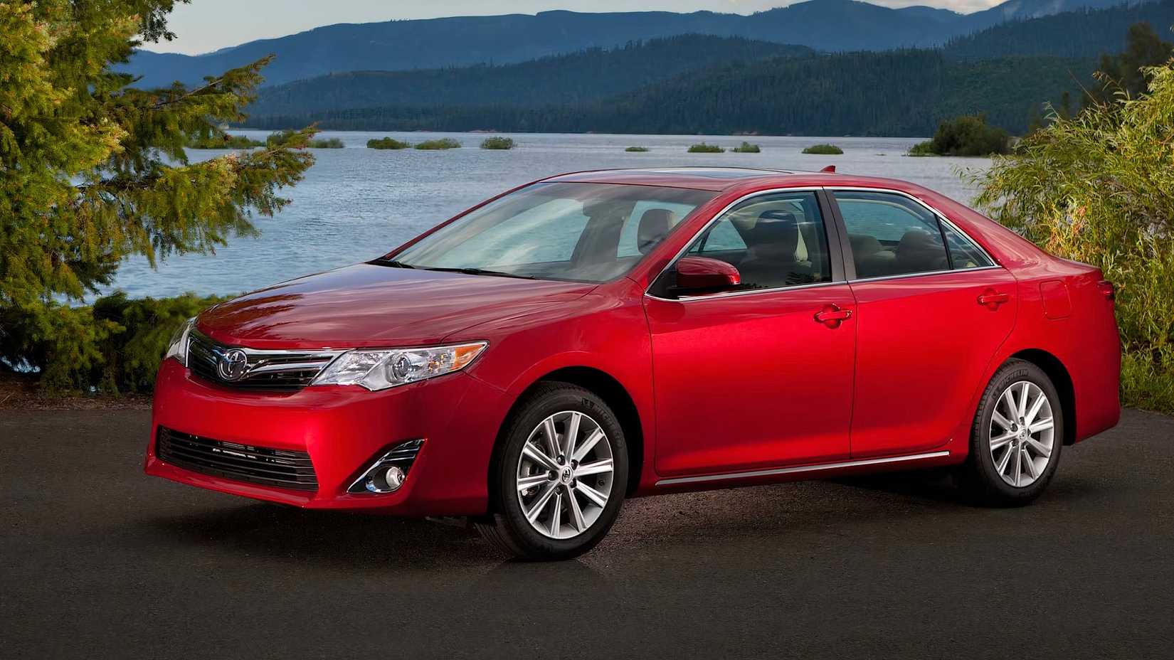 2014 Toyota Camry in red Posing in front of lake