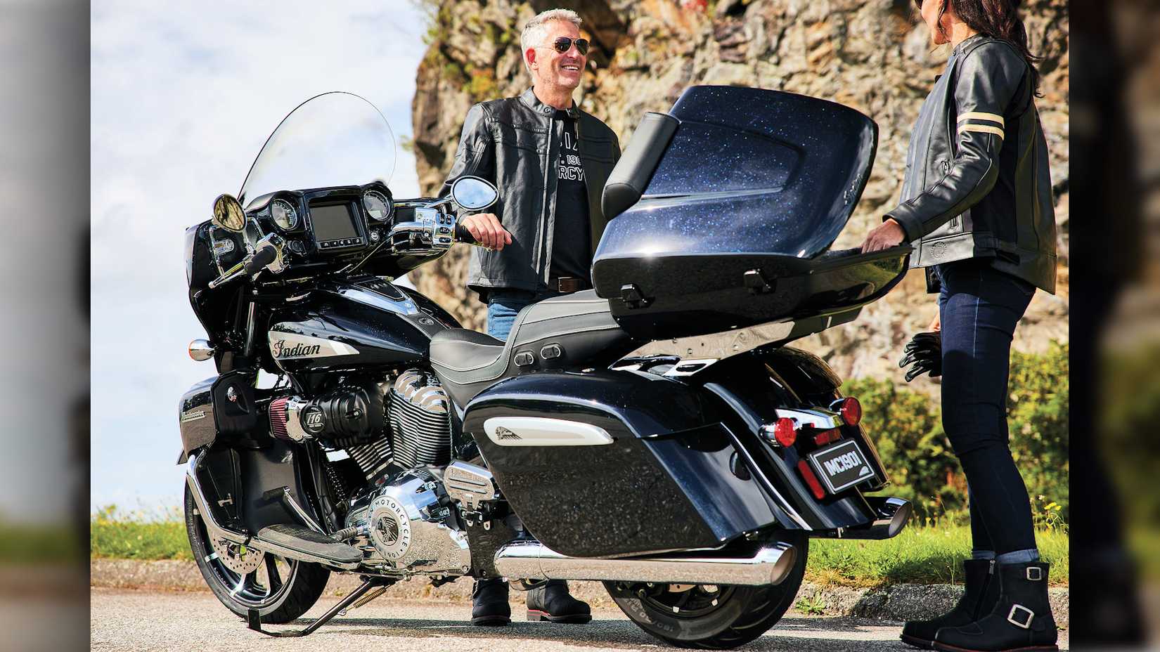 Rider and passenger standing next to an accessorized  2024 Indian Roadmaster Limited