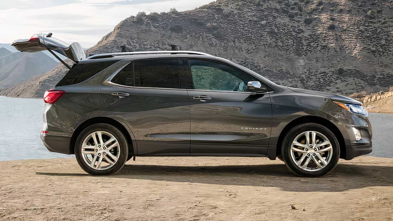 Tiro lateral do Chevrolet Equinox 2019-2021 estacionado na areia com o porta-malas aberto