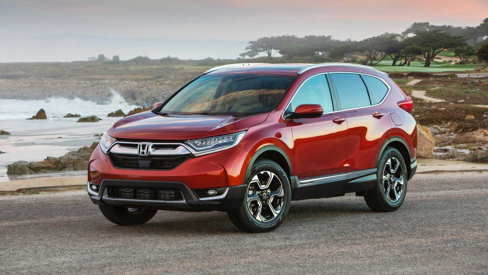 2024 Honda CR-V Hybrid em vermelho posando em frente ao litoral