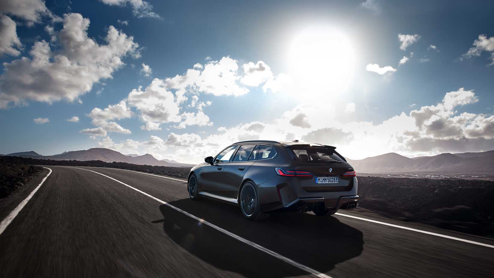 2025 BMW M5 Touring em cinza dirigindo em estrada de montanha