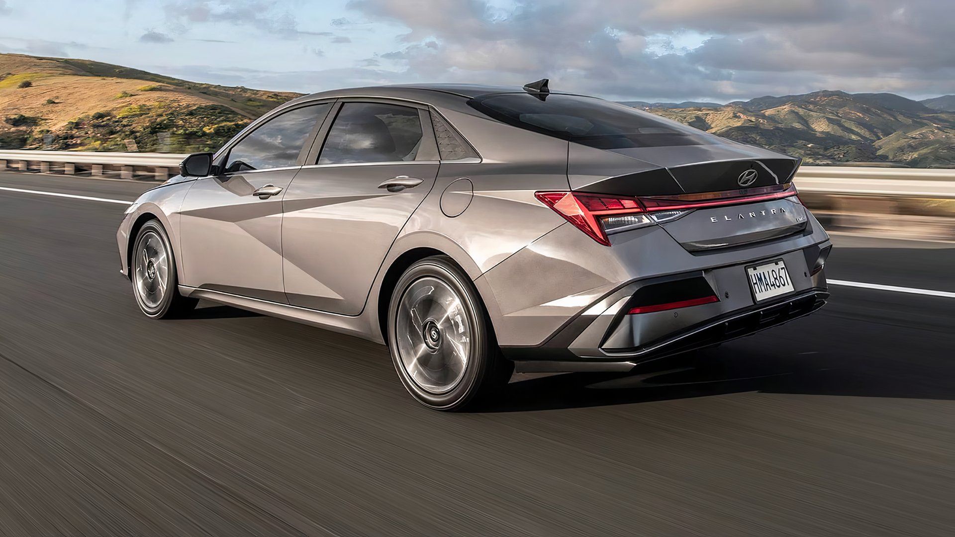A rear, left hand-side shot of a 2024 Hyundai Elantra speediing doen the road