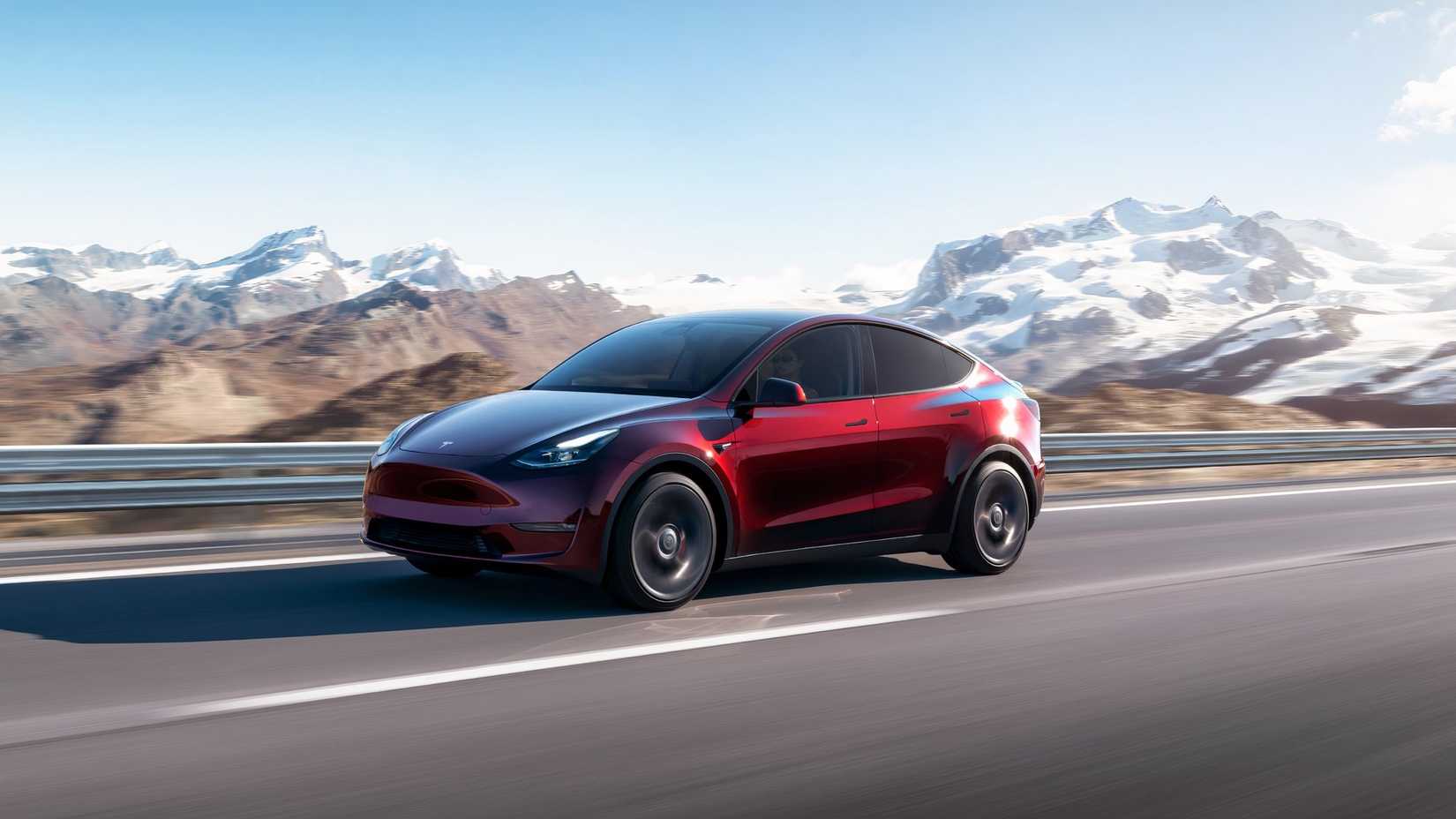 A red Tesla Model Y is driving.