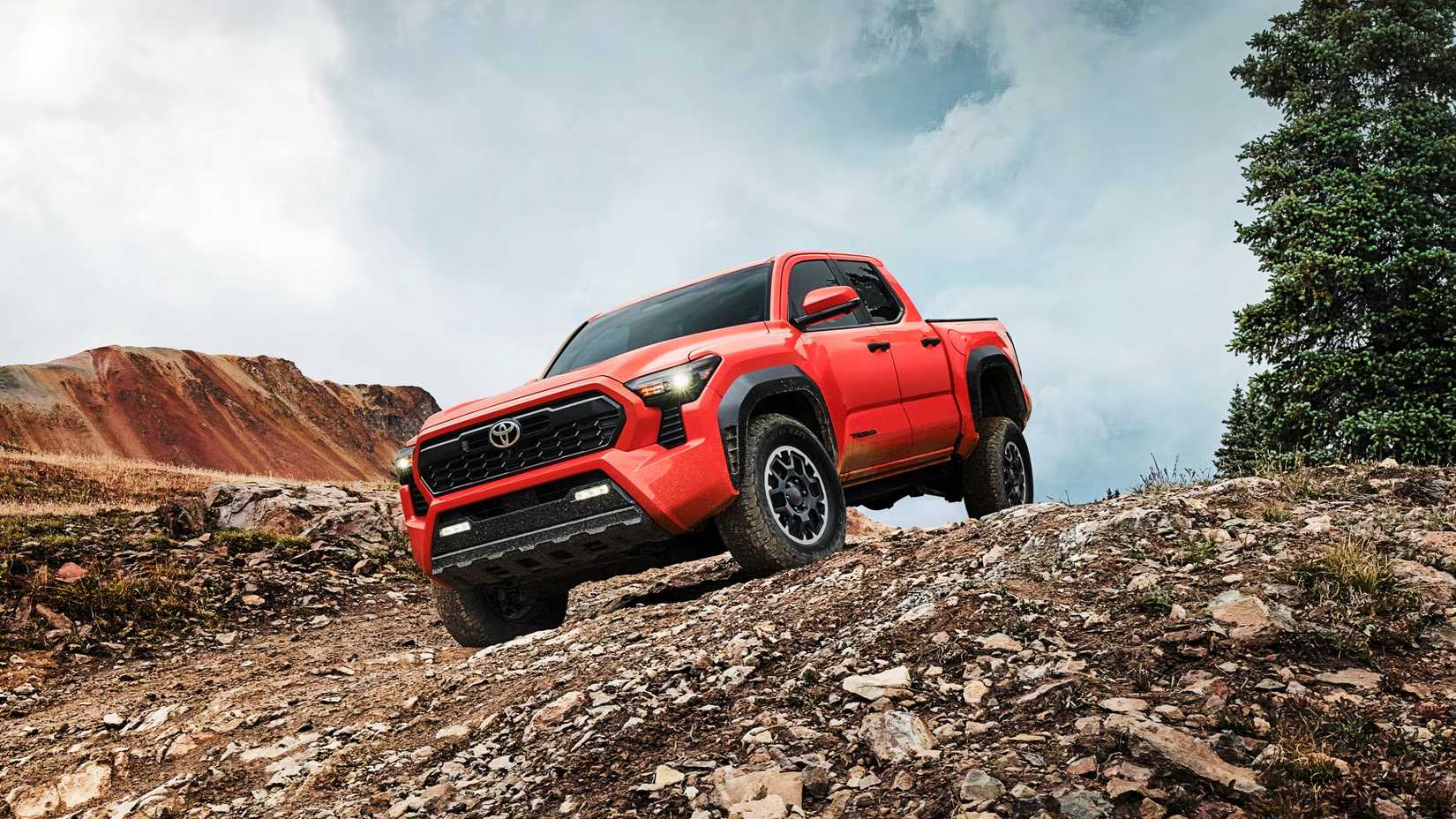 An orange Toyota Tacoma iForce Hybrid Max traversing down a hill. 