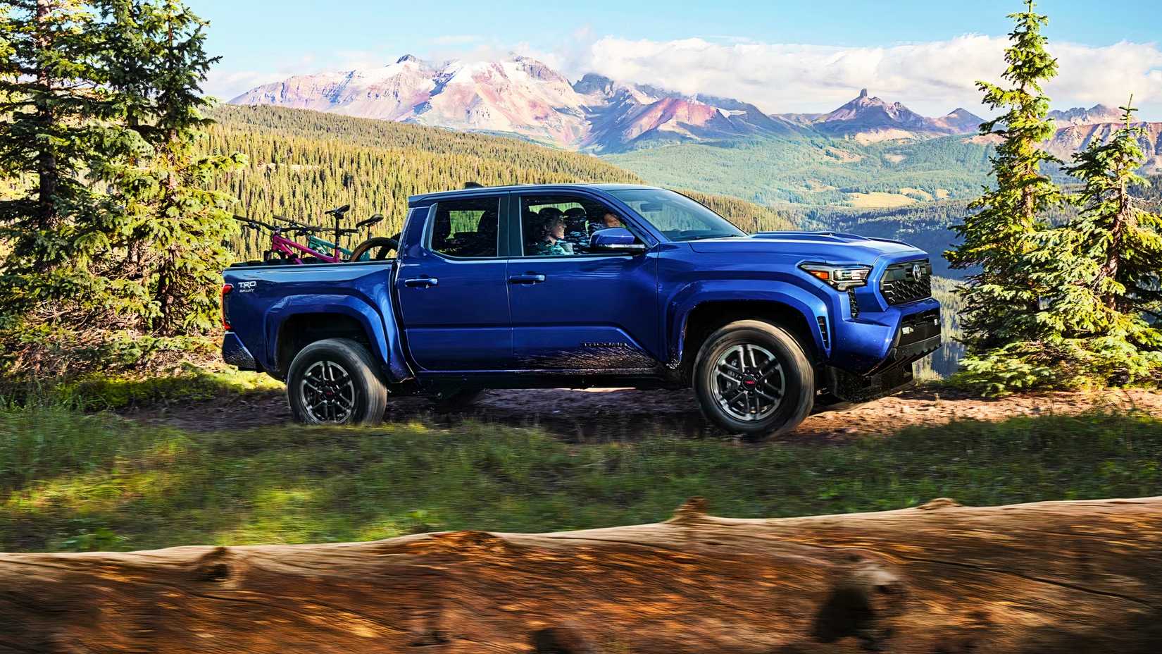 A blue Toyota Tacoma i Force Max pickup truck is driving. 