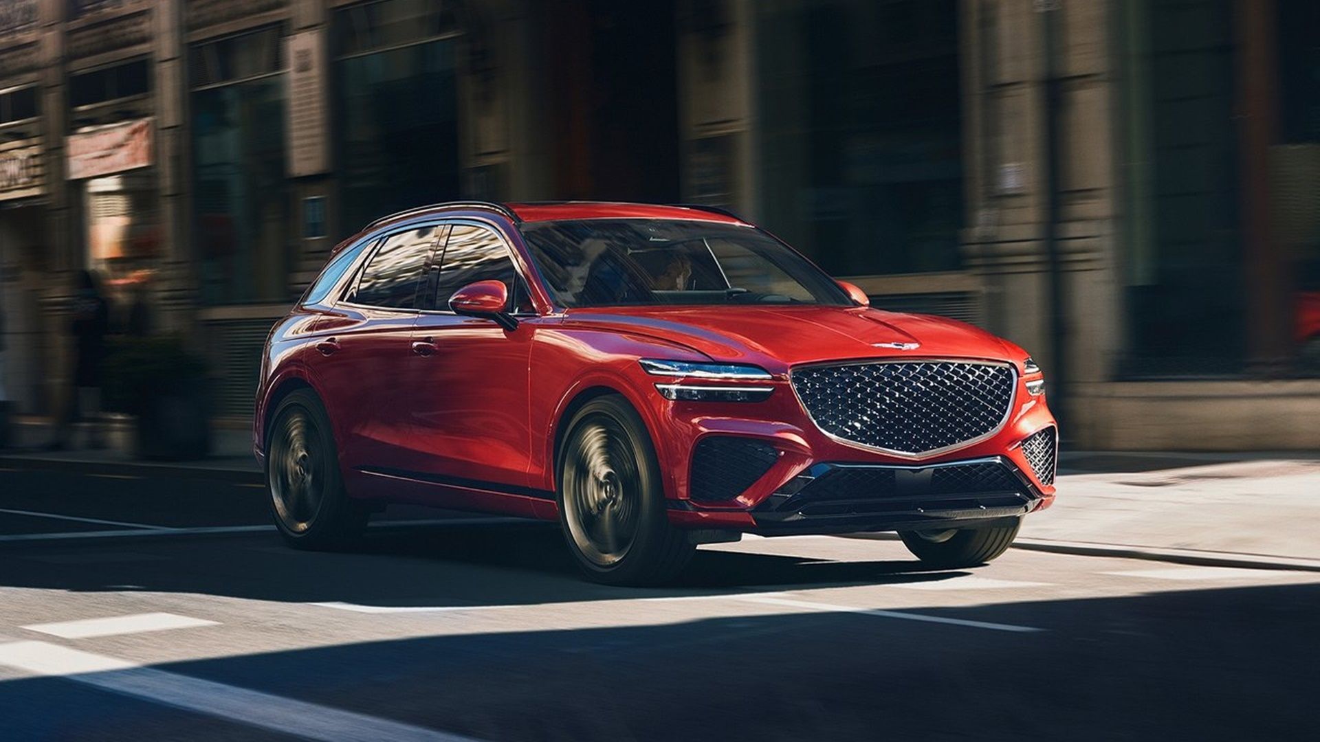2023 Genesis GV70 in red driving on city sreet