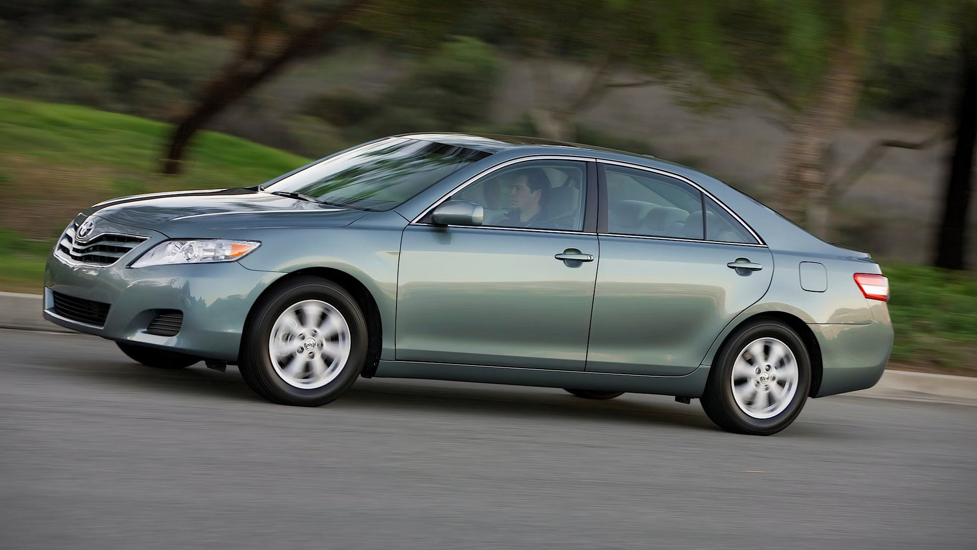 2011 Toyota Camry in green/blue driving along suburban street