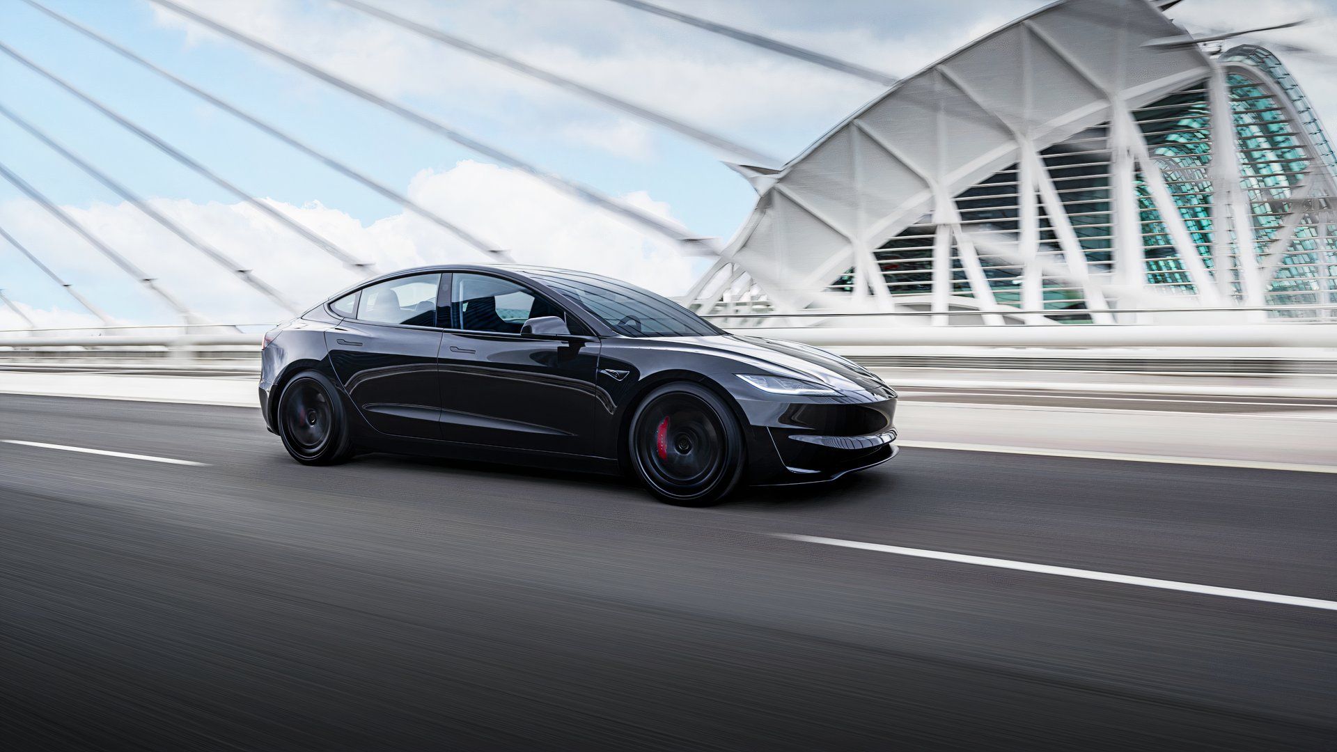 Um Tesla Model 3 preto está passando em uma ponte.