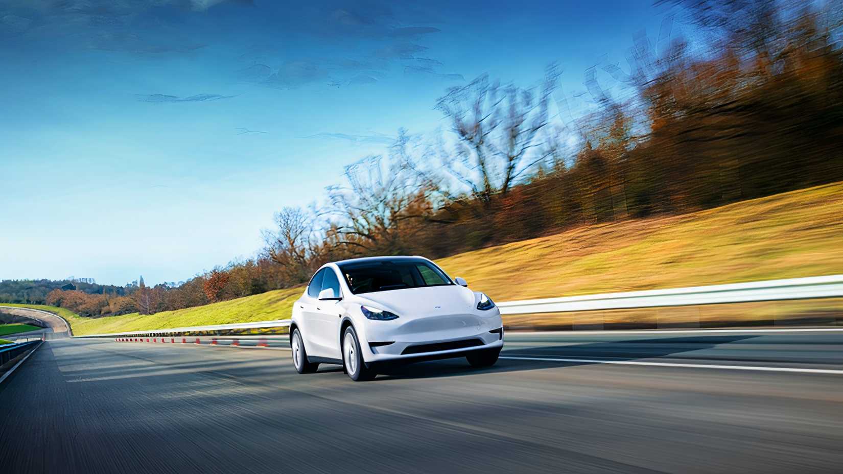 Um pequeno SUV elétrico Tesla Model Y branco está dirigindo na estrada.