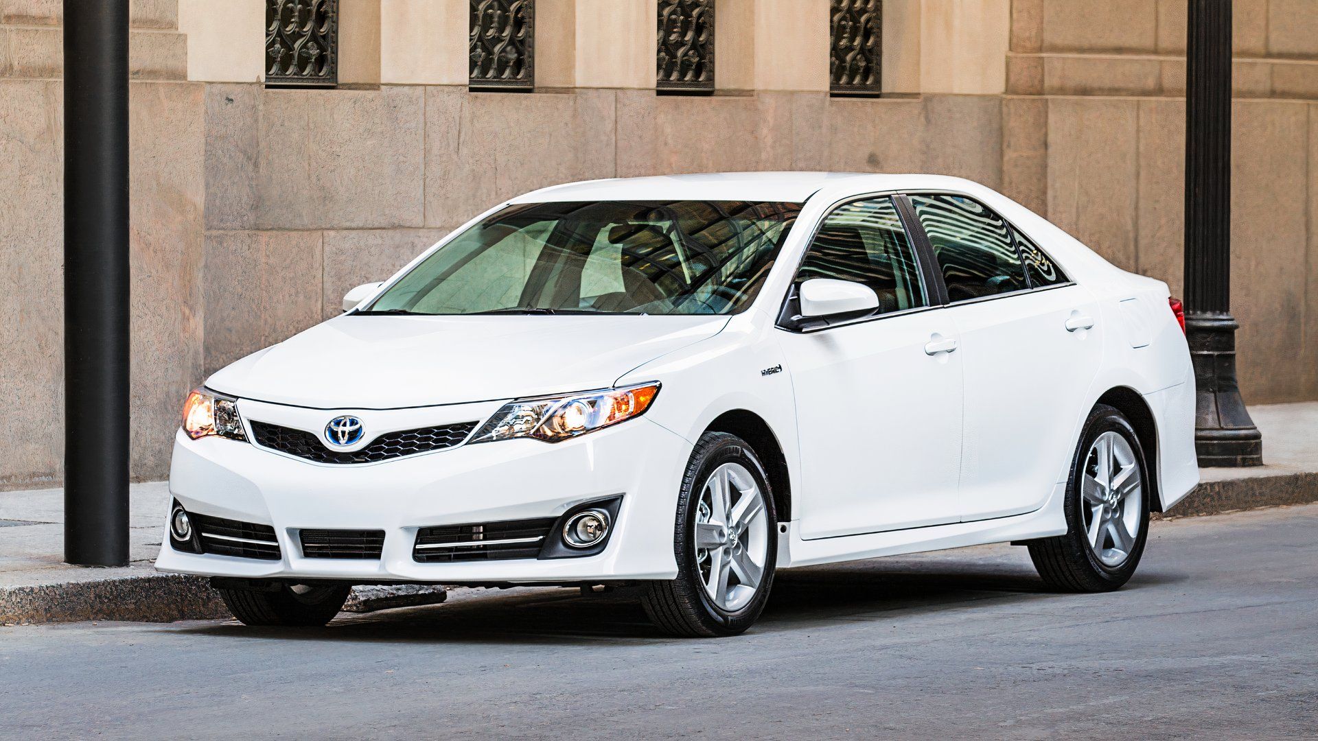 A white 2014 Toyota Camry Hybrid midsize hybrid car. 