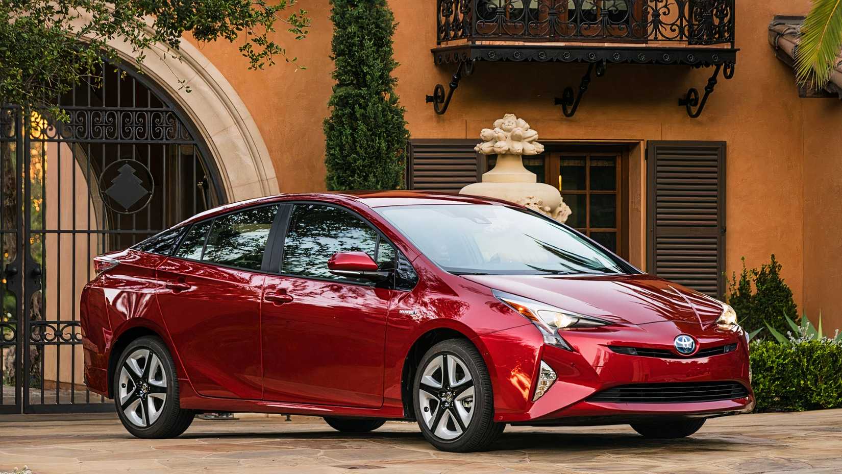 A red 2018 Toyota Prius hatchback is parked. 
