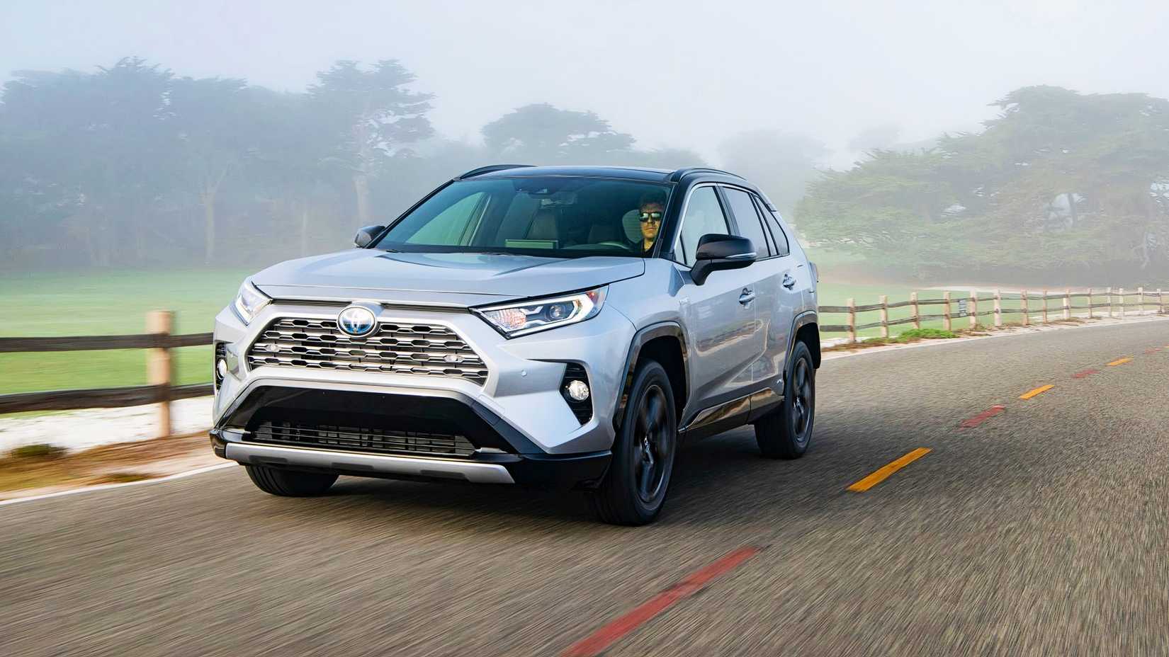 A gray 2021 Toyota RAV4 Hybrid small hybrid SUV is driving on the road. 