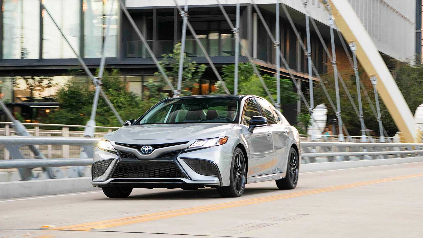 A gray 2022 Toyota Camry Hybrid is driving on the road. 
