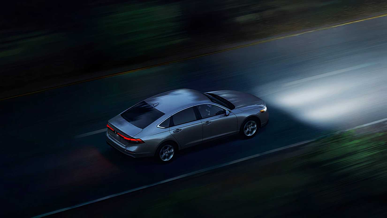 Um Honda Accord Hybrid 2024 cinza está dirigindo à noite.