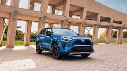 Um pequeno SUV híbrido Toyota RAV4 Hybrid 2024 azul está estacionado.