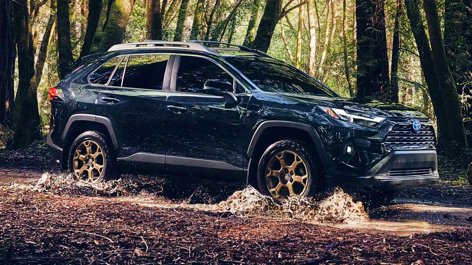 A blue 2024 Toyota RAV4 Hybrid Woodland Edition is driving off-road. 