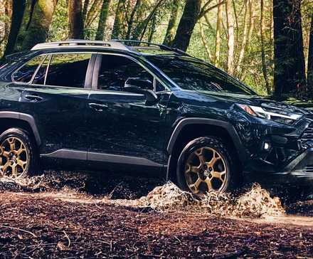 Um Toyota RAV4 Hybrid Woodland Edition 2024 azul está dirigindo off-road.