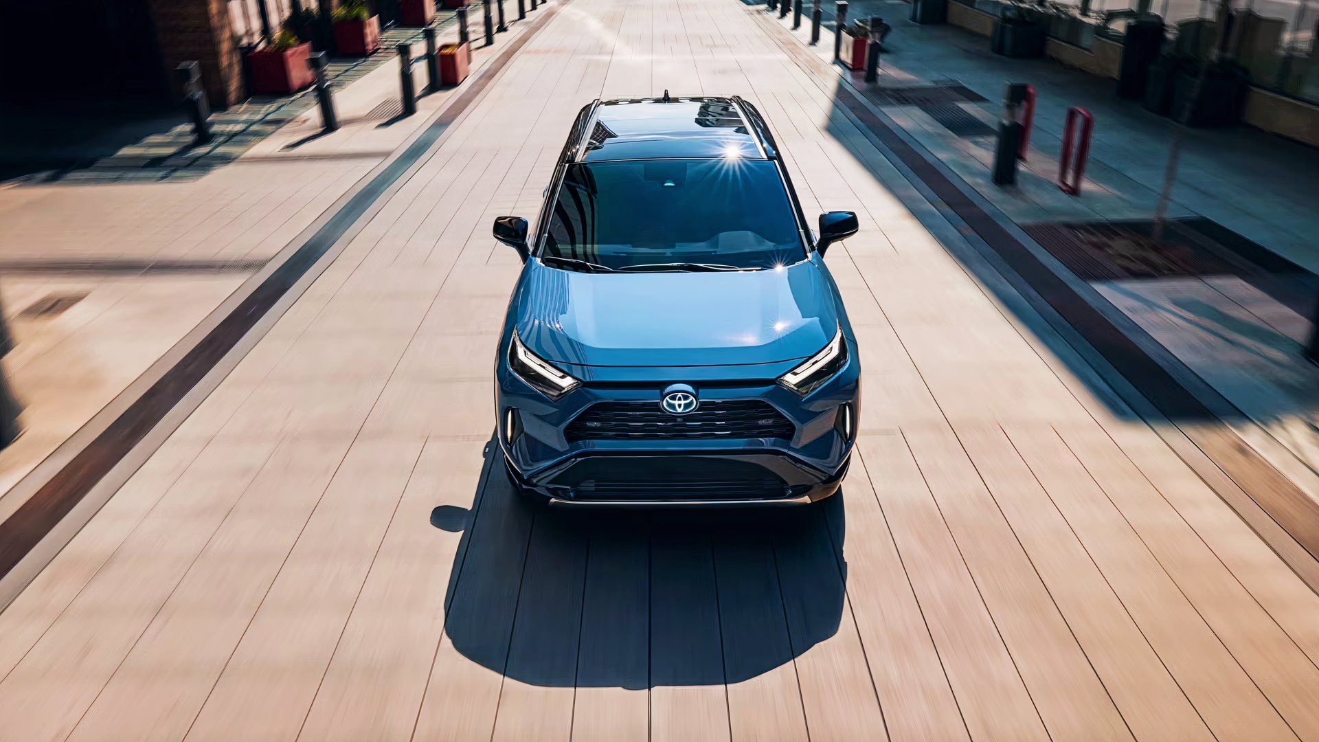 A blue 2024 Toyota RAV4 Hybrid small hybrid SUV is driving. 