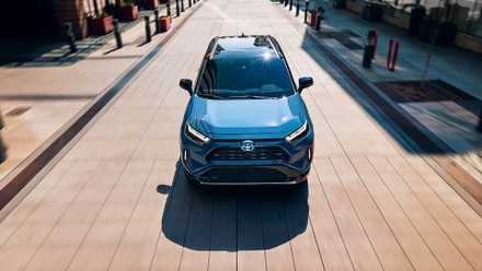 Um pequeno SUV híbrido Toyota RAV4 Hybrid 2024 azul está dirigindo.