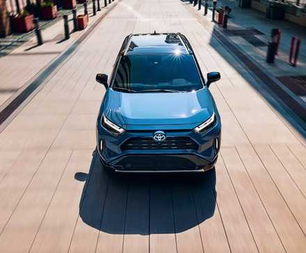 A blue 2024 Toyota RAV4 Hybrid small hybrid SUV is driving.