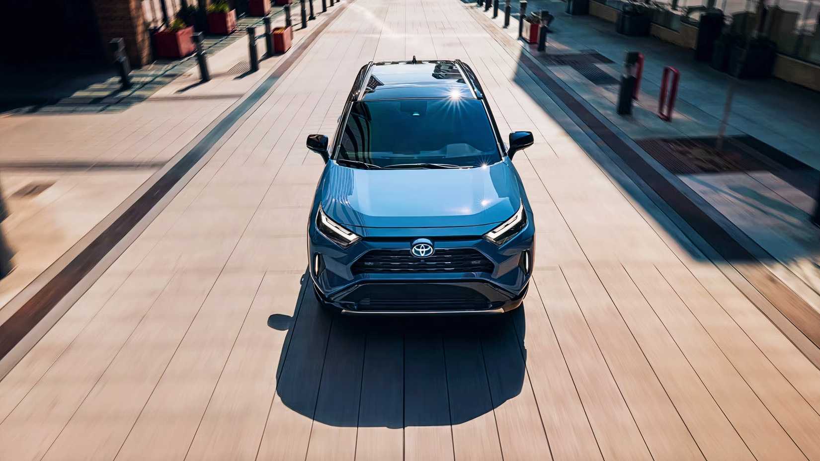 A blue 2024 Toyota RAV4 Hybrid small hybrid SUV is driving.