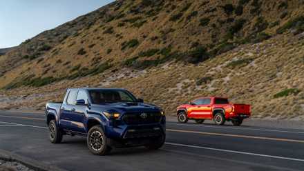 Modelos 2024 Toyota Tacoma em azul e laranja dirigindo em rodovia deserta