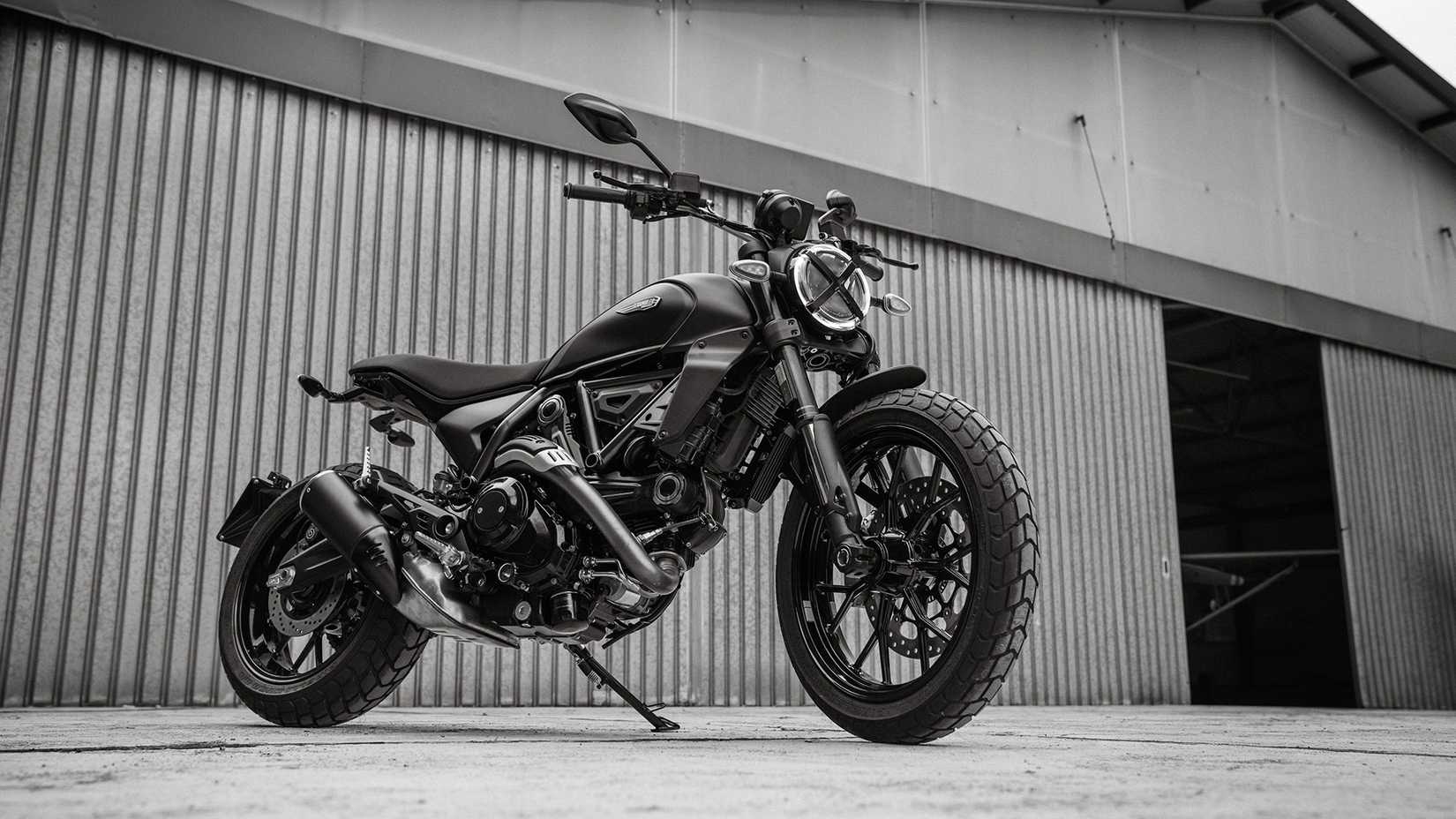 2025 Scrambler Icon Dark estacionado do lado de fora de um hangar