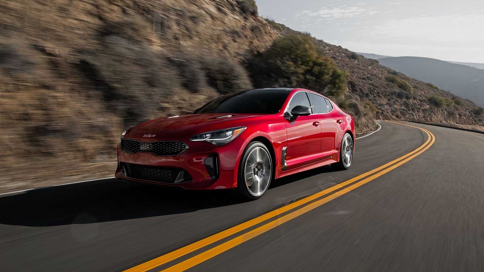 A front 3/4 shot of a 2023 Kia Stinger GT2 driving around a corner on a mountain road