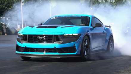 Vista frontal de três quartos de um Ford Mustang Dark Horse azul fazendo burnouts