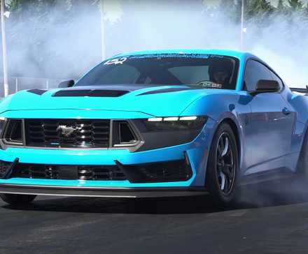 Vista frontal de três quartos de um Ford Mustang Dark Horse azul fazendo burnouts