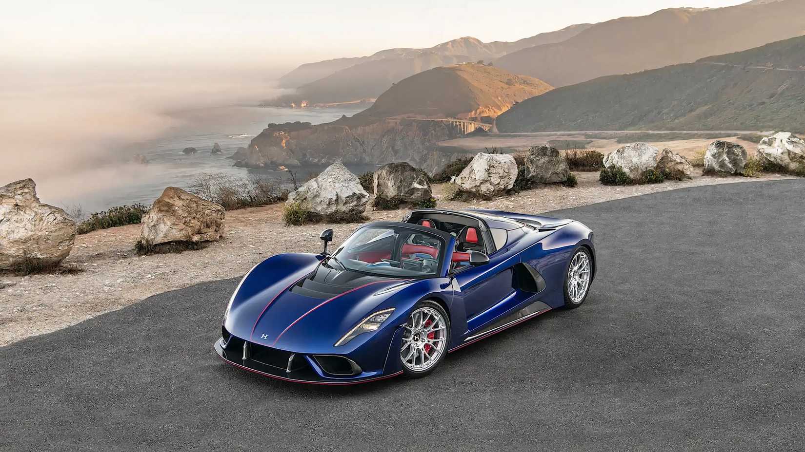 2022 Hennessey Venom F5 Roadster em azul posando em frente a uma estrada de montanha