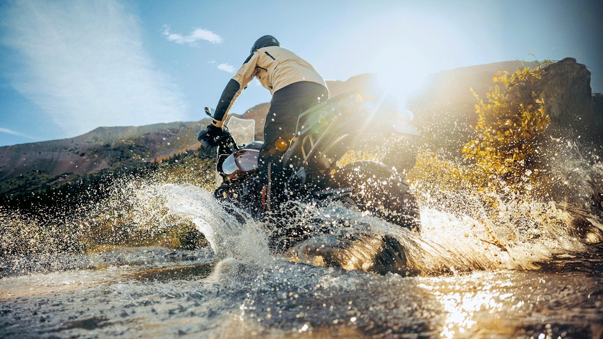 Piloto em uma Harley-Davidson Pan America 1250 Special 2024 chapinhando em um riacho