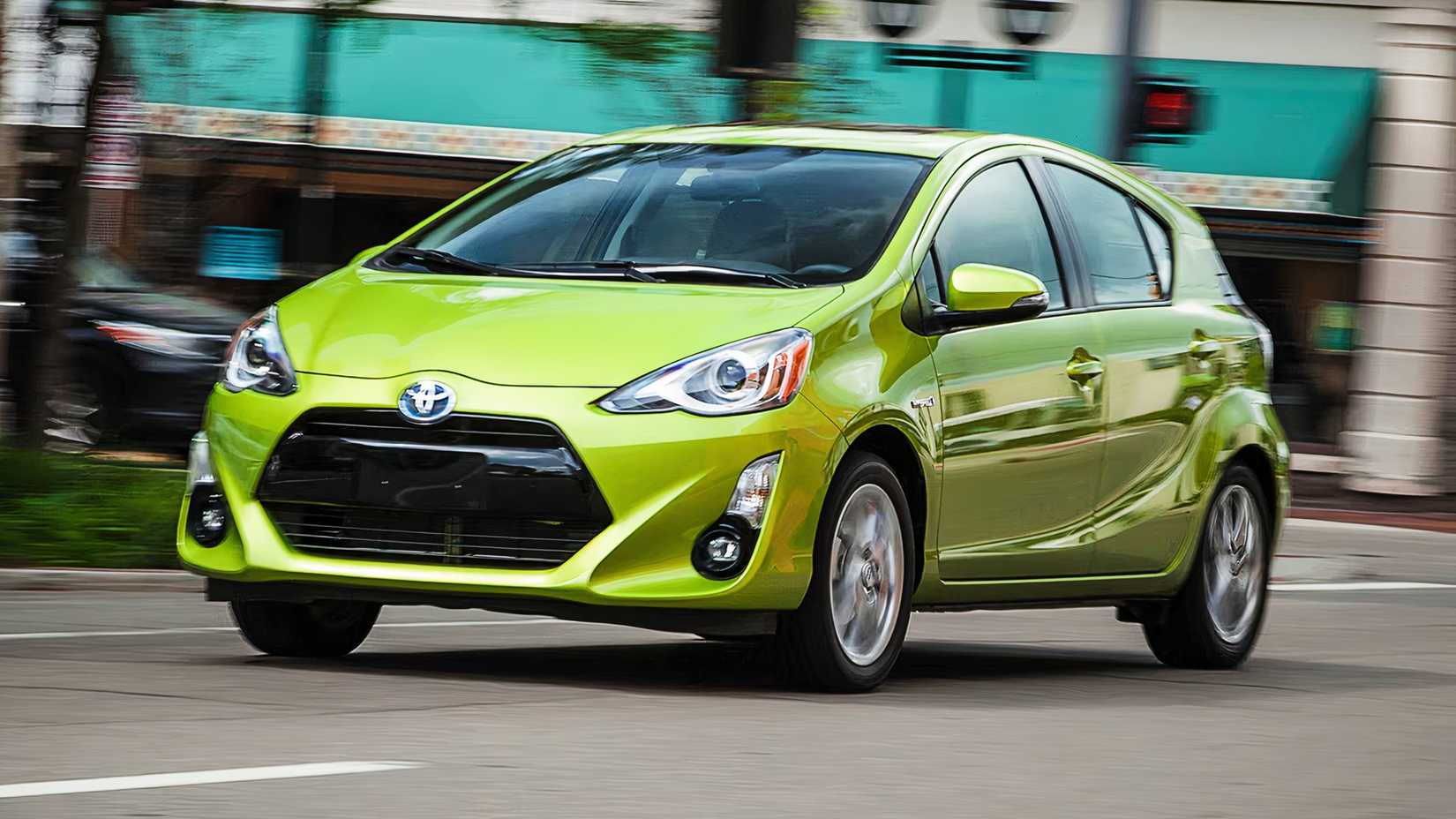 A green 2015 Toyota Prius hatchback hybrid is driving on the road. 