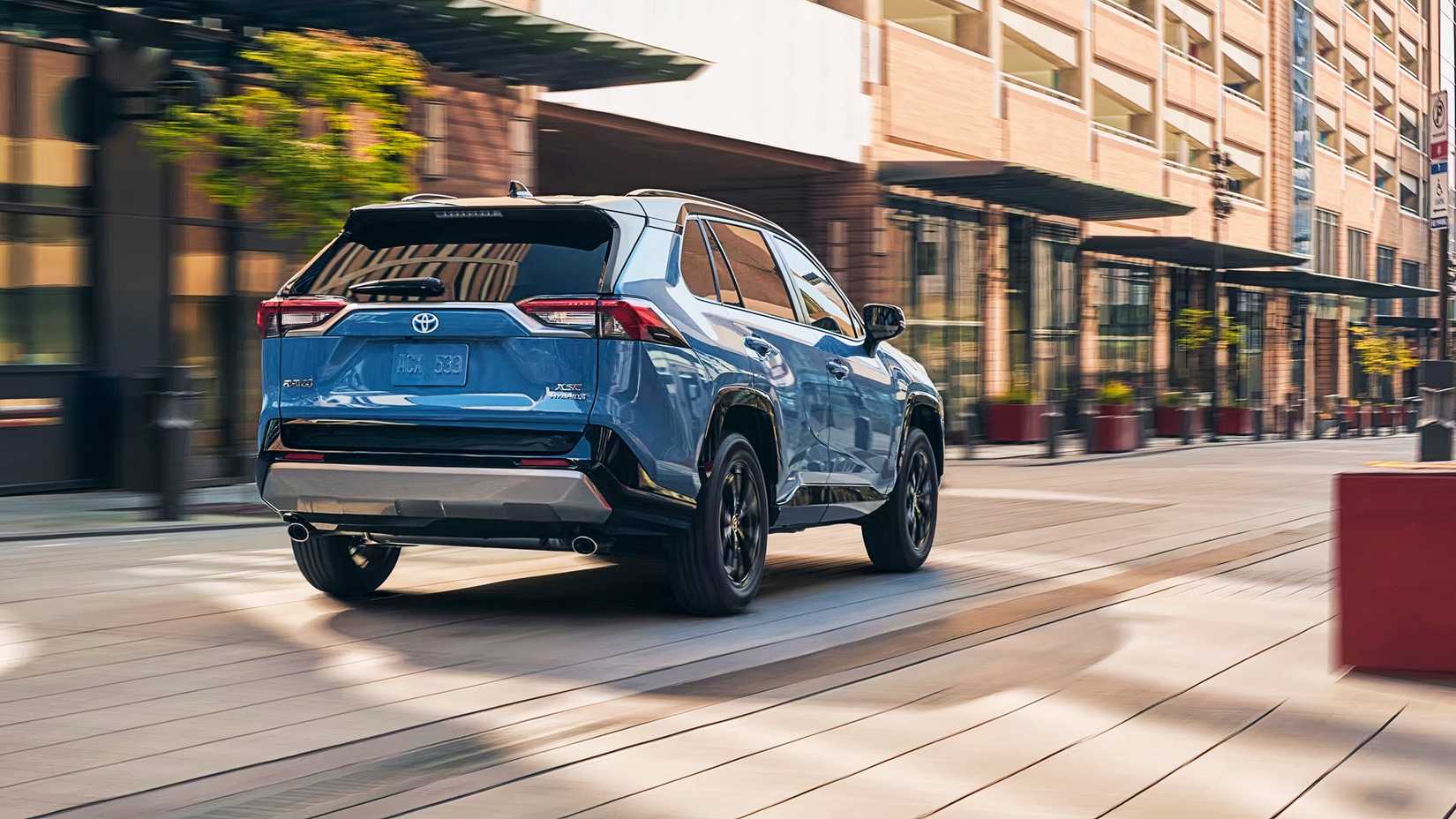 A blue 2024Toyota RAV4 Hybrid small hybrid SUV is driving on the road. 