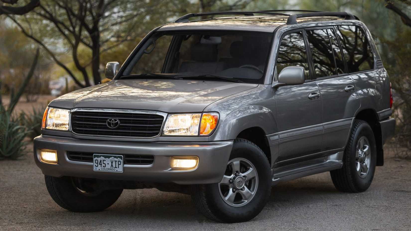 Toyota Land Cruiser 2001 em prata estacionado em frente a árvores