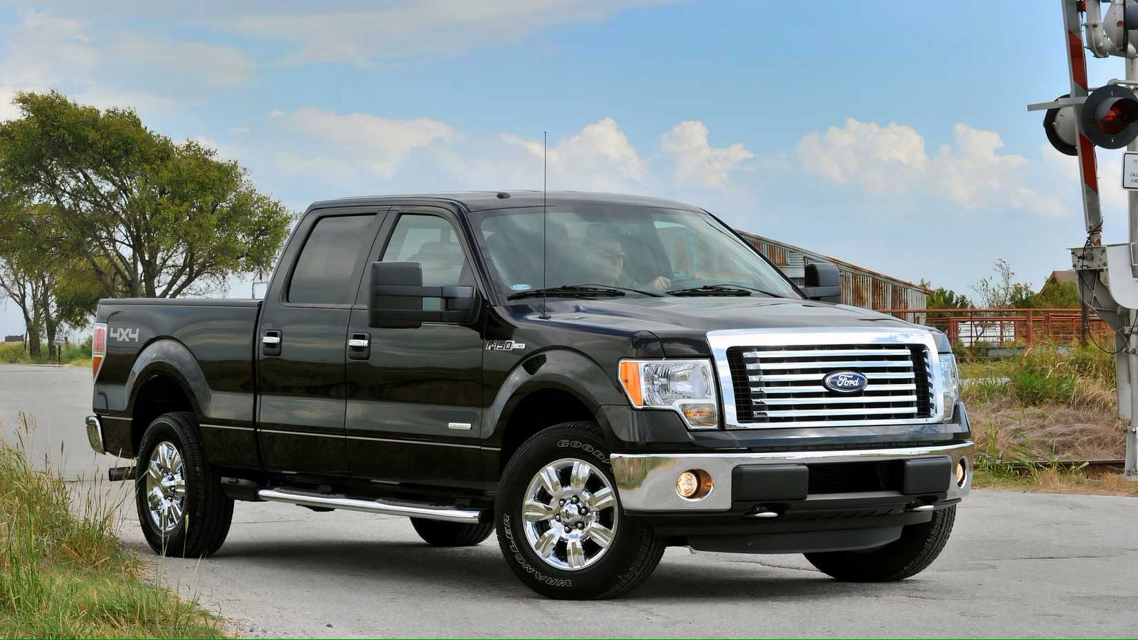 2011 Ford F-150 in black parked in front of level crossing