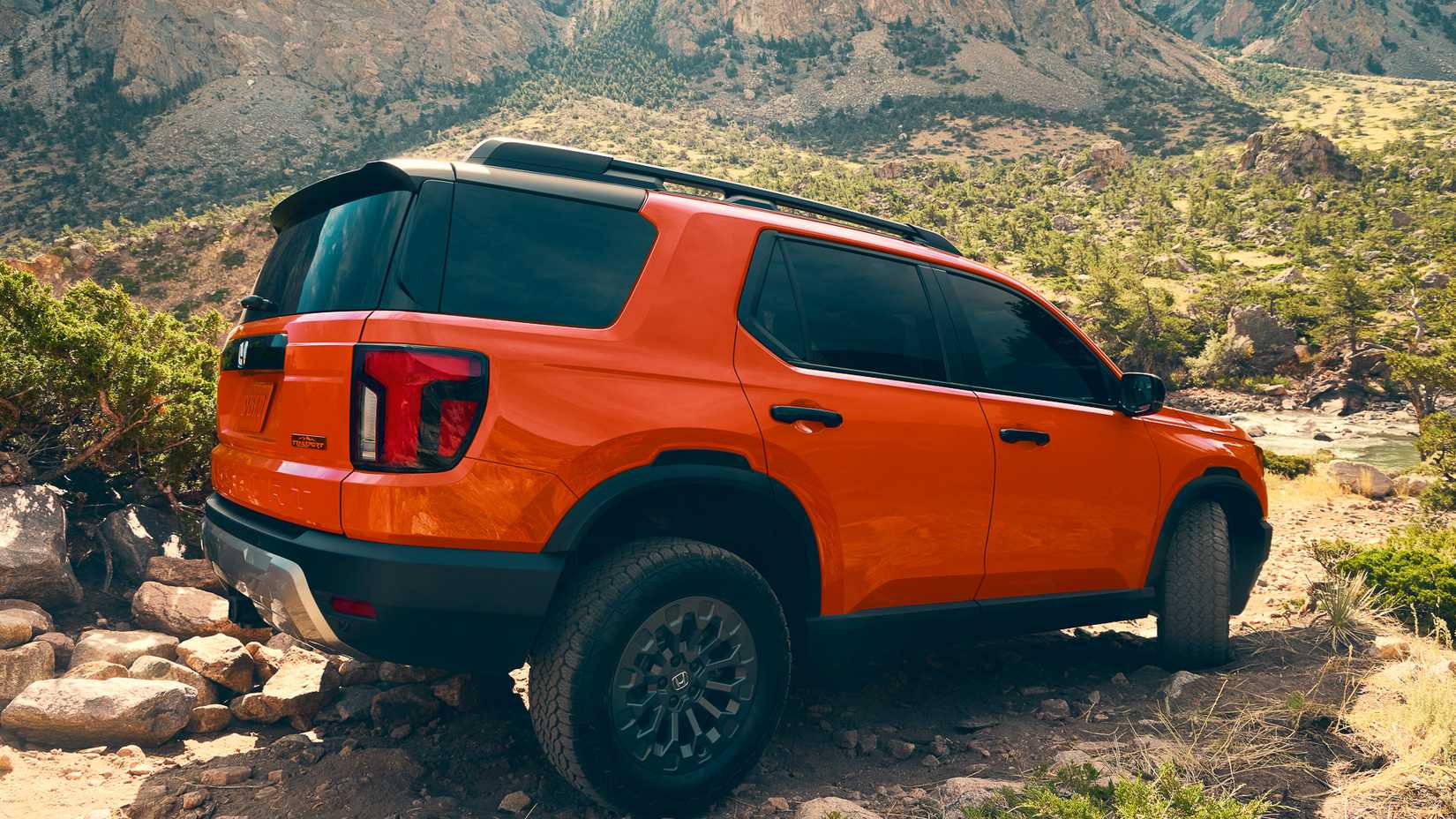 Rear 3/4 action shot of 2026 Honda Passport in orange driving off-road